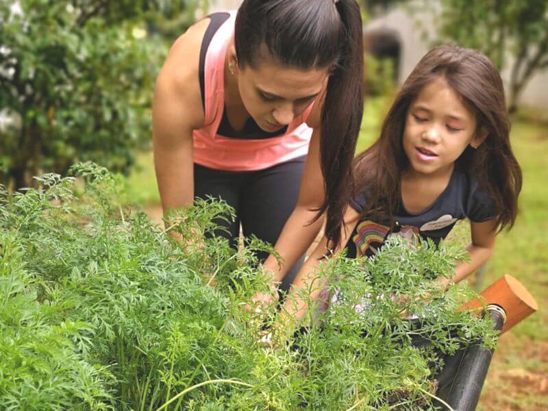 Duas irmãs plantando na horta do condomínio