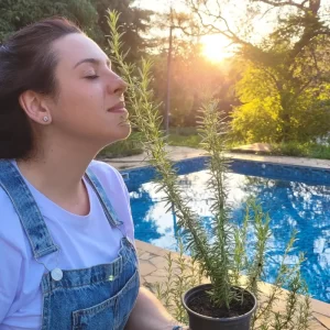 Mulher apreciando aroma de alecrim em paisagem ao por do sol.