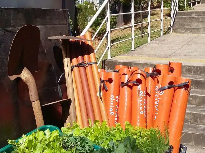 Ferramentas de jardim e mudas de alface prontas para plantio em condomínio.