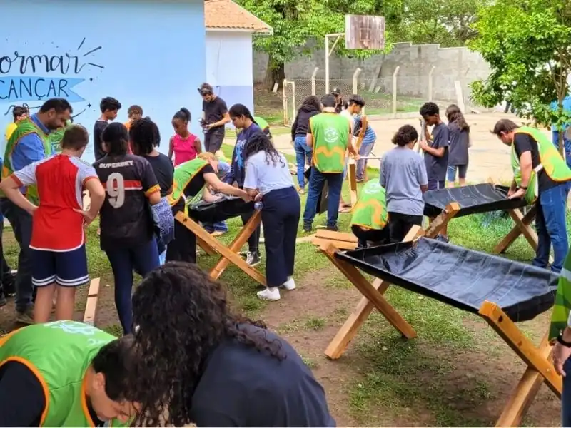 Vista lateral de um pátio escolar com vários canteiros elevados sendo preparados por alunos e equipe do projeto Escola Transforma.