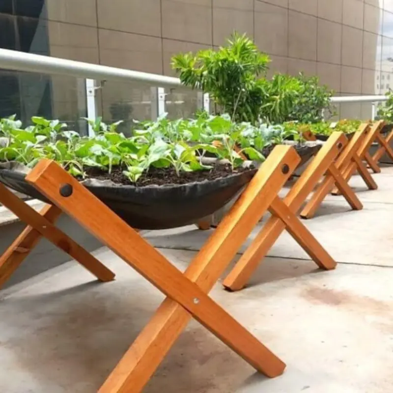 Horta em terraço corporativo com vista urbana, horta suspensa com verduras e temperos para sustentabilidade na empresa.